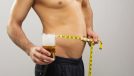 measuring beer belly and holding glass of beer, concept of how to get rid of your beer gut