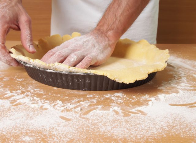 man pressing pastry crust over tin