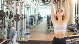 fit woman doing dumbbell overhead presses, concept of strength exercises to prevent belly fat